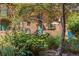 A lush garden view shows green shrubs and trees in front of a brick building with blue doors and trim at 930 Acoma St # 108, Denver, CO 80204