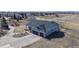 An aerial view of a blue two-story house with a two-car garage and concrete driveway in a suburban setting at 14701 Yosemite St, Brighton, CO 80602