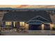 Inviting home with a three-car garage, brick accents, and a charming front porch illuminated at dusk at 14701 Yosemite St, Brighton, CO 80602
