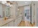 Bathroom featuring double vanity, wood flooring, granite countertops, and entry to bedroom at 5428 Forest View Rd, Parker, CO 80134