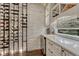 A wine room is equipped with custom shelving, beverage cooler, stone wall and a wet bar at 5428 Forest View Rd, Parker, CO 80134