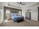 Primary bedroom features a tray ceiling, wood accent wall, and an abundance of natural light at 8172 S Langdale Way, Aurora, CO 80016