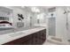 Bathroom features a double sink vanity, frameless mirror, modern lighting, and shower with glass doors at 8958 Southurst St, Littleton, CO 80129