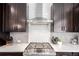 Close up of a kitchen with stainless steel hood over a gas cooktop and geometric tile backsplash at 8958 Southurst St, Littleton, CO 80129