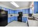 Efficient kitchen featuring blue cabinets, black appliances, and a window at 1282 S Troy St, Aurora, CO 80012