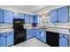 Well-equipped kitchen with blue cabinets, black appliances, and ample counter space at 1282 S Troy St, Aurora, CO 80012