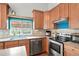 Functional kitchen with wood cabinets, stainless steel appliances, ample counter space, and a garden window offering natural light at 21733 Saddlebrook Dr, Parker, CO 80138
