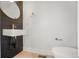 Modern powder room features shiplap accent wall, round mirror and wall mounted sink with gold fixtures at 1907 W Elk Pl, Denver, CO 80211