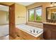 Bright bathroom featuring a relaxing soaking tub, tile surround, and a large window overlooking a green landscape at 8286 W 108Th Pl, Broomfield, CO 80021