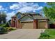 Attractive home featuring a three-car garage, brick accents, lush lawn, and blooming flower beds at 8286 W 108Th Pl, Broomfield, CO 80021