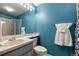 Full bathroom with blue accent wall, a cream-colored vanity, toilet, and a shower with a blue curtain at 9911 Perry Ct, Westminster, CO 80031