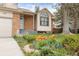 Charming home exterior with brick accents, a manicured lawn adorned with tulips, and a unique arched window detail at 9911 Perry Ct, Westminster, CO 80031