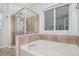 Bathroom featuring soaking tub with tile surround and glass enclosed shower near bright window at 23841 E Alabama Dr, Aurora, CO 80018