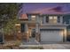 Charming two-story home with stone accents, a covered porch, and an attached two-car garage at dusk at 23841 E Alabama Dr, Aurora, CO 80018