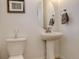 Cozy powder room featuring a pedestal sink, modern fixtures, and a decorative mirror at 27655 E Geddes Pl, Aurora, CO 80016