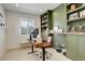 Well-lit home office featuring custom green built-ins, a large window, and comfortable workspace at 27655 E Geddes Pl, Aurora, CO 80016