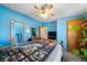 Bedroom features blue walls, a wood bed frame, a ceiling fan and a view to the bathroom at 7573 Woodruff St, Fort Lupton, CO 80621