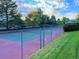 Fenced community tennis court with well-maintained surface and surrounding green landscape at 1470 S Quebec Way # 275, Denver, CO 80231