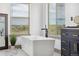 A soaking tub with a view, set against marble flooring, perfect for relaxation in this bright bathroom at 2400 Ventress Ct, Bennett, CO 80102