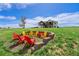 An outdoor fire pit surrounded by colorful Adirondack chairs sits on a lush green lawn at 2400 Ventress Ct, Bennett, CO 80102