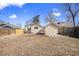 Rear view showing the back of the home and detached garage with a large, fenced yard at 1449 Clinton St, Aurora, CO 80010