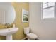 Stylish powder room with a pedestal sink, a round mirror, and a contemporary wall color at 13838 Honey Hush Trl, Parker, CO 80134