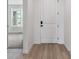 Bright hallway featuring sleek wood floors, a modern white door, and a glimpse of the living room at 39172 Clymer St, Elizabeth, CO 80107