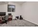 A bedroom with grey carpet, a window, and a desk with computer setup is staged for use at 10197 E Mississippi Ave, Denver, CO 80247