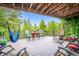 Back deck view with seating, a dining table and wooded scenery at 11094 Thomas Dr, Conifer, CO 80433