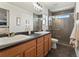 Modern bathroom with double sinks, wood cabinets, a frameless glass shower, and contemporary fixtures at 4125 Coriander St, Castle Rock, CO 80109
