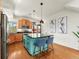 Bright kitchen with stainless steel appliances, wood cabinets, a blue island with bar seating and modern pendant lights at 4125 Coriander St, Castle Rock, CO 80109
