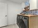 Functional laundry room with washer and dryer, butcher block folding counter, shelving, and stylish wallpaper accent at 4125 Coriander St, Castle Rock, CO 80109