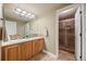 Bright bathroom with double sinks, wood cabinets, decorative mirror, and tiled shower at 1251 Double Eagle Ct, Castle Rock, CO 80104