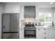 Modern kitchen boasts stainless steel refrigerator, oven, and custom range hood at 329 Lodgewood Ln, Lafayette, CO 80026