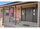 Inviting front porch with brick accents, dual seating benches, and a patriotic American flag on display at 18107 E Belleview Ln, Centennial, CO 80015