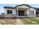 Backyard with covered porch and sliding glass doors on a home with white siding and decorative stonework at 3443 N Gold Bug Ct, Aurora, CO 80019
