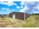 Exterior view of a large barn, with a white door, on a grassy lot under a blue sky at 10325 Cherrywood Dr, Parker, CO 80138