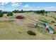 Aerial view of the red barn, horse shelters, and white fenced paddocks on the grassy property at 10325 Cherrywood Dr, Parker, CO 80138