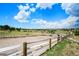 View of the horse arena with white fencing and a sprawling green landscape at 10325 Cherrywood Dr, Parker, CO 80138