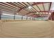 Vast indoor arena with sand footing, metal beams, and bright lighting at 10325 Cherrywood Dr, Parker, CO 80138