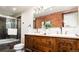 Unique bathroom featuring double sinks, a vintage wooden vanity, a brick accent wall, and a walk-in shower at 3519 Newton St, Denver, CO 80211