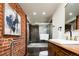Bathroom features a unique brick accent wall, soaking tub, and vanity with fixtures at 3519 Newton St, Denver, CO 80211
