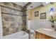 Stylish bathroom features a shower-tub combo with stone tile and a vanity with granite countertop at 8427 Chase Dr, Arvada, CO 80003