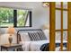 Cozy bedroom featuring a metal frame bed, black and white striped pillows, and a window with a view of trees at 8427 Chase Dr, Arvada, CO 80003