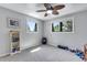Bright bedroom featuring neutral walls, gray carpet, two windows, and a ceiling fan for added comfort at 8427 Chase Dr, Arvada, CO 80003
