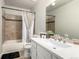 Bright bathroom featuring a large mirror, modern vanity, and tiled bathtub with shower curtain at 11105 E Alameda Ave # 204, Aurora, CO 80012