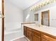 Bright bathroom features a large mirror with vanity lighting, a soaking tub and neutral tile at 11181 Main Range Trl, Littleton, CO 80127