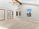 Bright primary bedroom boasts a ceiling fan, vaulted ceiling, ample windows, and large mirrored closet at 11181 Main Range Trl, Littleton, CO 80127
