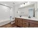Modern bathroom with dual vanity, wood cabinets, and a shower-tub combo at 9257 Truckee Ct, Commerce City, CO 80022
