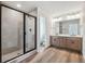 Modern bathroom with a glass shower, dual vanity, and wood cabinets at 9257 Truckee Ct, Commerce City, CO 80022